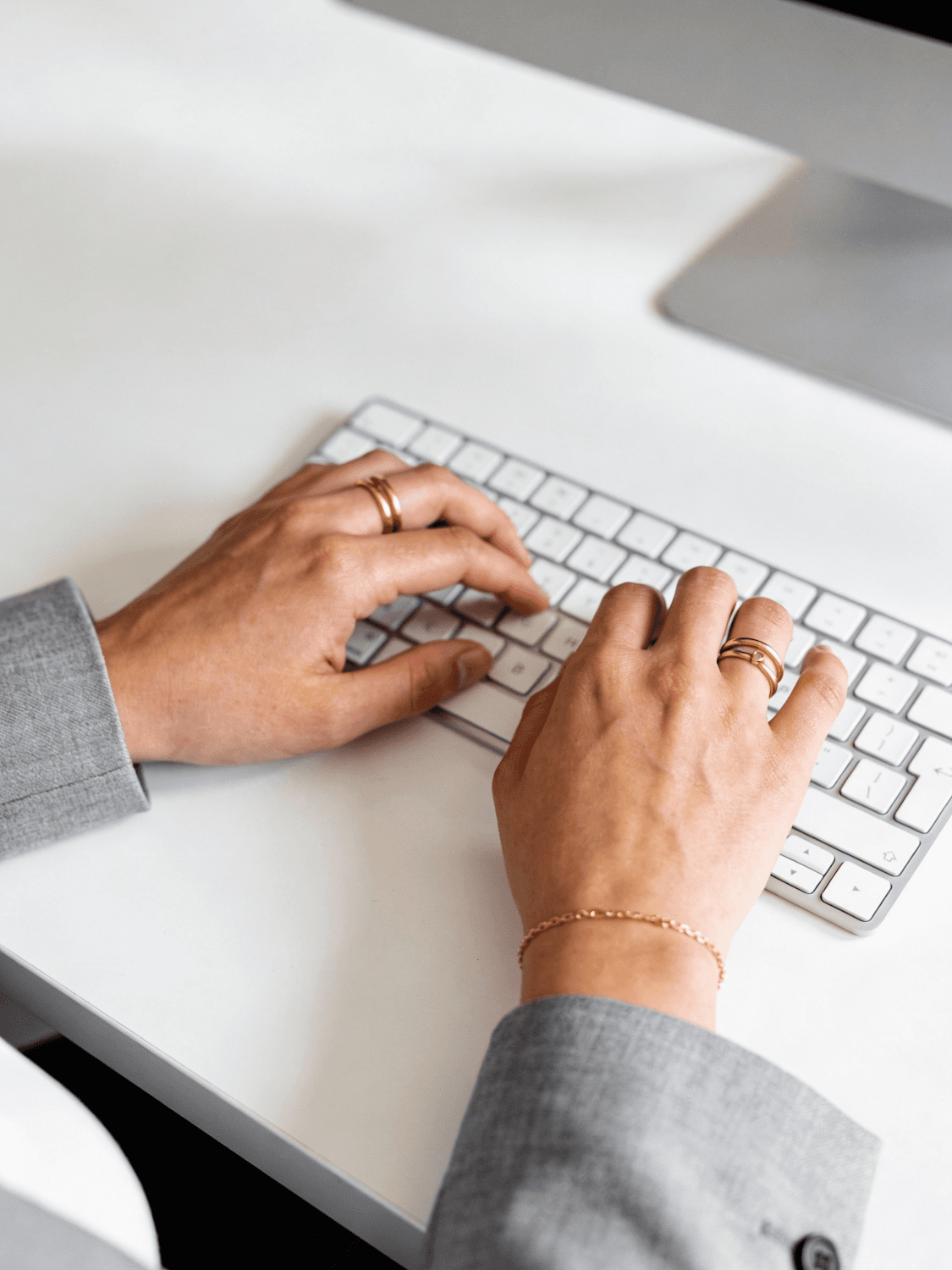 Hands typing on a pale keyboard at a clean, modern desk